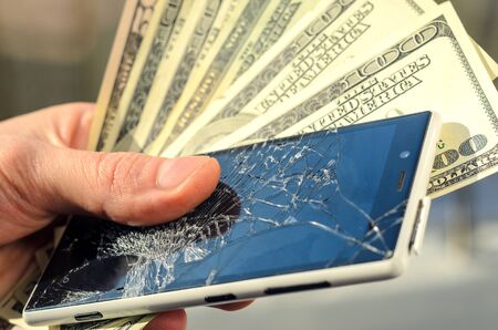 White Smartphone with broken screen in human hands on blured nature background. Need new smartphone, a waste of conceptの写真素材