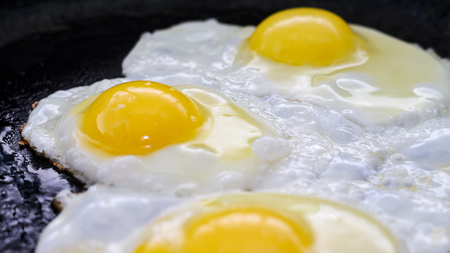 Fried eggs in a frying pan. Process of cooking eggs closeup. Food Backgroundの写真素材