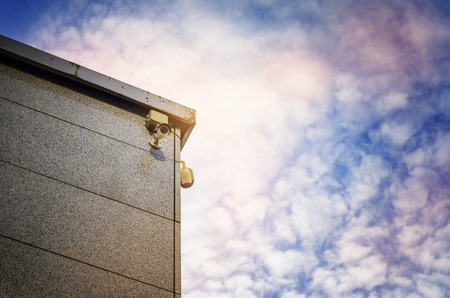 Two Security cameras on the side of an modern building against blue skyの写真素材