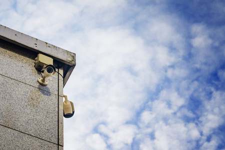Two Security cameras on the side of an modern building against blue skyの写真素材