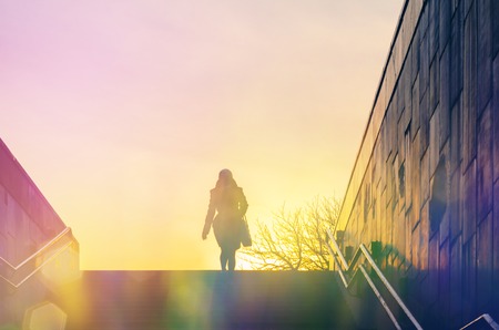 Blurred Abstract Background. Silhouette of a lonely woman climbing the stairs from an underpass. Concept of loneliness in city lifeの写真素材