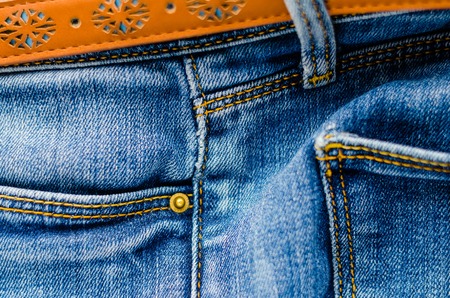 Detail of jeans trousers with brown leather belt close-up. Pockets, pants, belt loops, thick stitches. Elements of denim pants backgroundの写真素材