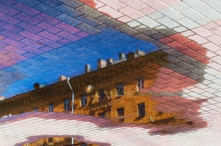 Reflection of the roof of the building in the water on the pavement. Cityscape abstract backgroundの写真素材