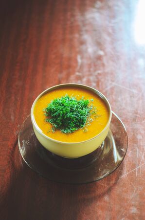 Pumpkin soup on a wooden table with a slice of chopped parsleyの写真素材