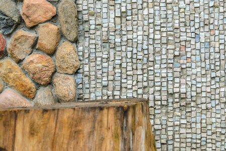 The junction of a cobblestone wall with wood and a shallow mosaic. Wall with various finishes with natural stoneand wood. Mixed finishing wallの写真素材