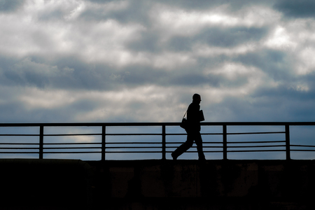 Silhouette of a walking man against a background against a cloudy sky. Rush conceptの写真素材