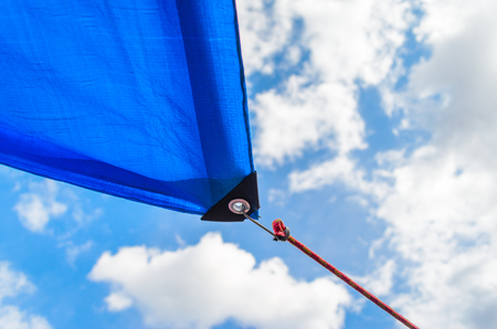 Awnings in sails shape over cloudy sky background. Detail of securing the tent from the sun to the cableの写真素材