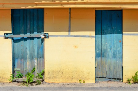 Yellow plastered facade with blue wooden doors. Yellow Wall Backgroundの写真素材