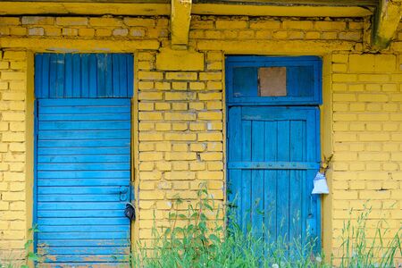 Closed blue wooden doors on yellow brick wall backgroundの写真素材
