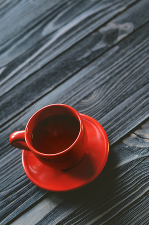 A cup for espresso is a classical form of red color on a wooden table. Free space for text placement. Blank backgroundの写真素材