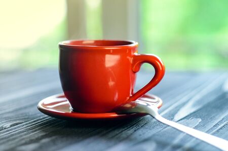A cup of red espresso on a wooden table in the cozy interior of a cafe