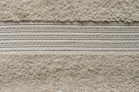 Element of beige color towel. Fleecy part and decorative element with braided pigtails. Texture is similar to the texture of a fleecy knotted-pile carpet.の写真素材