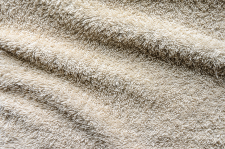 Casually lying towel of beige color. Folds on the surface of a beige towelbackgroundの写真素材