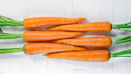 Geometrically laid out fresh carrots on a white wooden table top view. Fresh carrots on white...