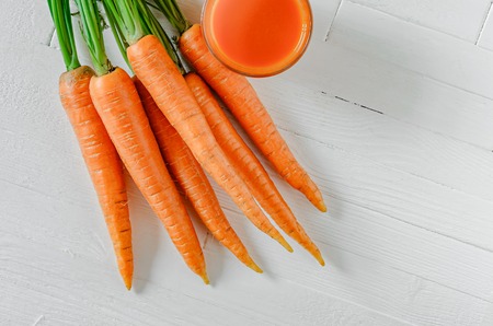 Healthy carrot smoothie in a jar with carrots on white wooden table top view. Healthy food background conceptの写真素材