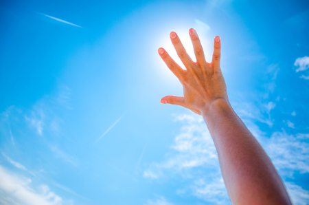 Silhouette of a Hand against a Sunset. Sun rays between fingers. Summer sunny dayの写真素材
