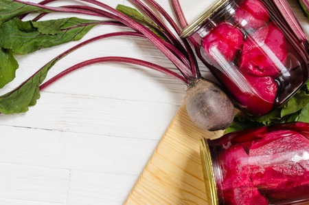 Two glass jars with canned beets home made and fresh organic beets with haulm on a white wooden background top view with copy space for your text message top vew.の写真素材