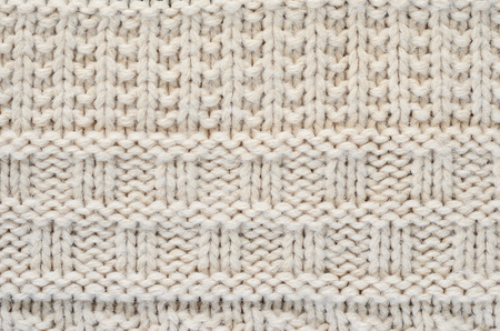 The texture of a knitted sweater is a thick beige string. Part of a sweater with various kinds of...