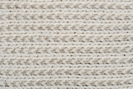 The texture of a thick knitted sweater beige close-up. Uniform knitting patternの写真素材