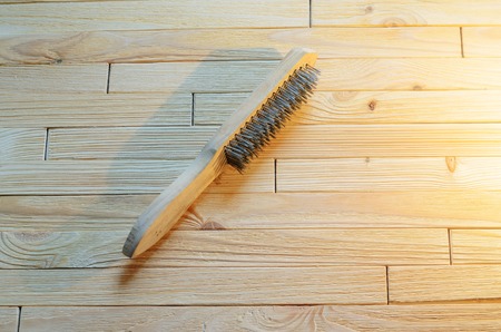 Brush with steel bristles on a wooden table. Tool for carpentry with an empty space for textの写真素材