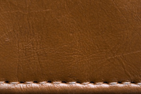 Texture of brown leather with stitches. Element of leather clothing close-up. Seams on leather productsの写真素材