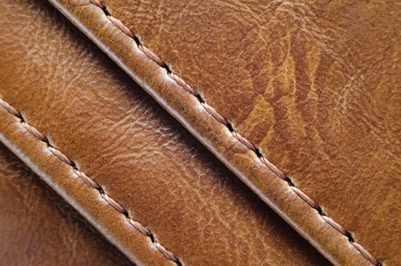 Texture of brown leather with stitches. Element of leather clothing close-up. Seams on leather productsの写真素材