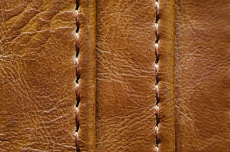 Texture of brown leather with stitches. Element of leather clothing close-up. Seams on leather productsの写真素材