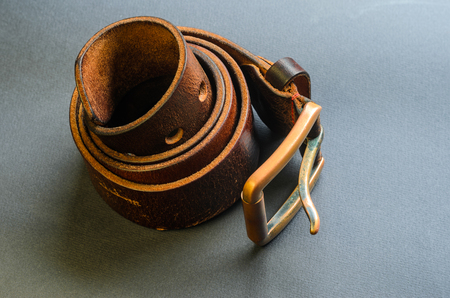 Twisted brown leather belt with copper buckle on gray background top viewの写真素材