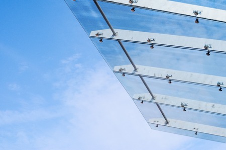 Glass Canopy Against Blue Sky Background. Fastening Elements of Glass Canopy on Modern Buildingの写真素材