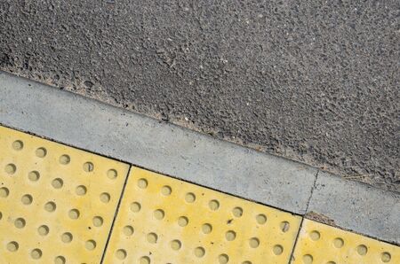 Adjoining Pavement with a Tactile Tile for Blind Peoples and an Asphalt Road. Joint of Road Surfaces Textureの写真素材