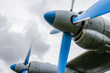Close up of airplane turboprop engine with propeller, parts of aircraft fuselage, wings and tail on a cloudy sky backgroundの写真素材