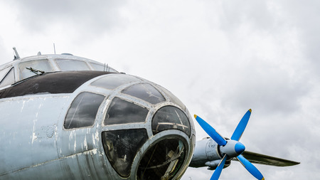 Close up of airplane turboprop engine with propeller, parts of aircraft fuselage, wings and tail on a cloudy sky backgroundの写真素材