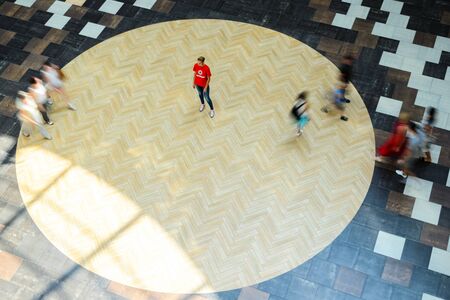 Silhouettes of Walking People in the Atrium of a Large Public Building, View from Above. Blur in Motion, Long Exposure. Abstract Backgroundの写真素材