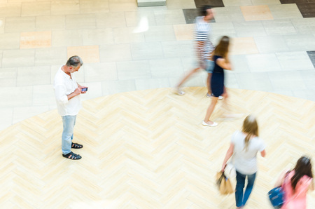 Silhouettes of Walking People in the Atrium of a Large Public Building, View from Above. Blur in Motion, Long Exposure. Abstract Backgroundの写真素材