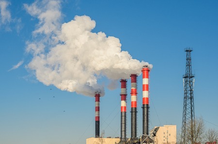 Plant pipes with smoke against clear blue sky.