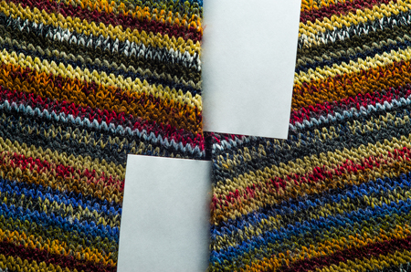Colorful Knit Fabric Texture with White Card of Paper as Blank Space. Macro View of a Knitted Sweater. Blank Backdrop Mock-Upの写真素材