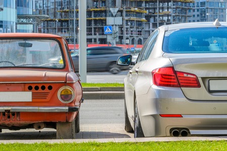 Rear view of two cars of different eras standing side by side in the city. The concept of technology developmentの写真素材