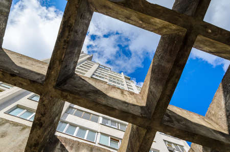 View of a Facade of Residential Building and Blue Sky with White Clouds Through a Canopy from Concrete Beams. Architecture Backgroundの写真素材