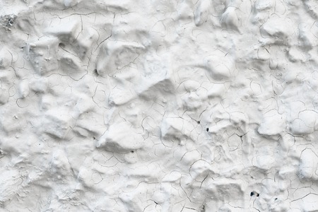 Rough Concrete Wall Decoration, Painted White. White Concrete Wall with Many Protruding Stones.の写真素材