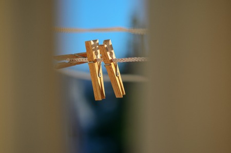 Two wooden clothespins on a clothesline against a blue sky backgroundの写真素材