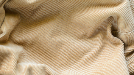Texture of Soft Velvet Fabric with Folds Closeup. Texture of Beige Velvet Clothes. Textile Fabric of Corduroy as Backgroundの写真素材