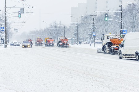 Snow plow trucks column removes snow from the city road. Snowstorm in the city - seasonal abstract motion blur backgroundの写真素材