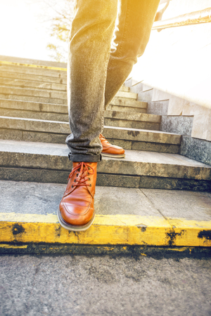 Man in beautiful brown leather shoes walks the granite stairs in an urban environment. Blank...