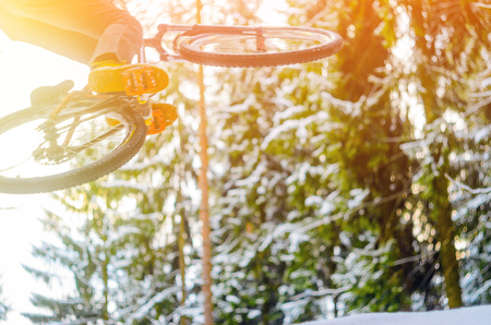Motion in blur silhouette of a cyclist in a jump. Mountain biking on trails in a snowy forest. Extreme winter sport. Bike rider flies through the air. Abstract blurred backgroundの写真素材