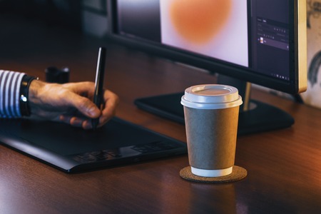 Desktop side view. Computer Graphics Tablet Diary Cup of coffee Hand. Concept for website banner, mockup, background, presentation and marketing materialの写真素材