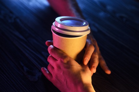 A loving couple at the table. Top view. Hands Paper cup Plastic cap Wooden table Beautiful lightの写真素材
