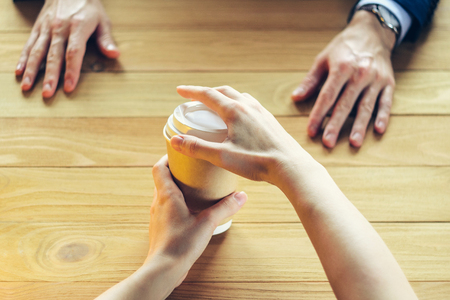 Barista serves coffee to a man. Hand Paper cup Plastic cap Wooden table Break Blazer. Coffee Break Conceptの写真素材