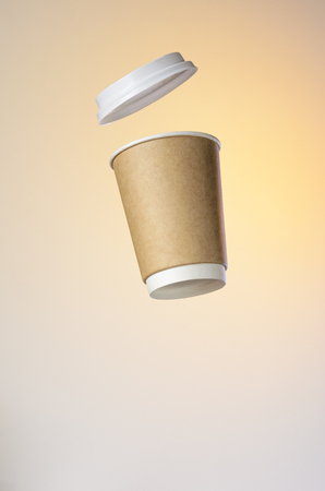Paper cup of coffee with a plastic cap levitates in the air. Paper Cup Layout For Advertising. Empty Place for Logo Placementの写真素材