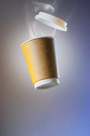 Levitating paper cup with evaporation from a hot coffee. Clubs of steam from a hot drink. Paper Cup Layout For Advertising. Paper cup of coffee with a plastic cap levitates in the airの写真素材