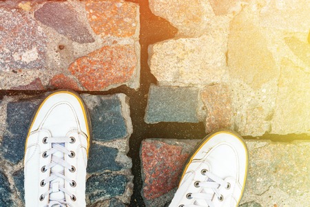 White Leather Sneakers on Granite Pavement Background Top View. Copy Space